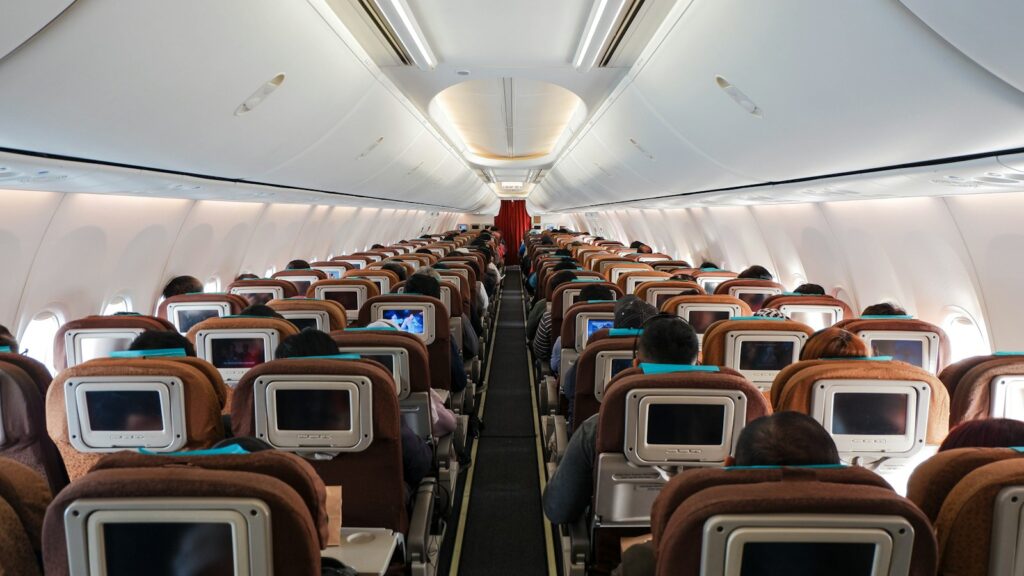 Looking down the aisle of a long-haul aircraft cabin with rows of seats and seatback screens