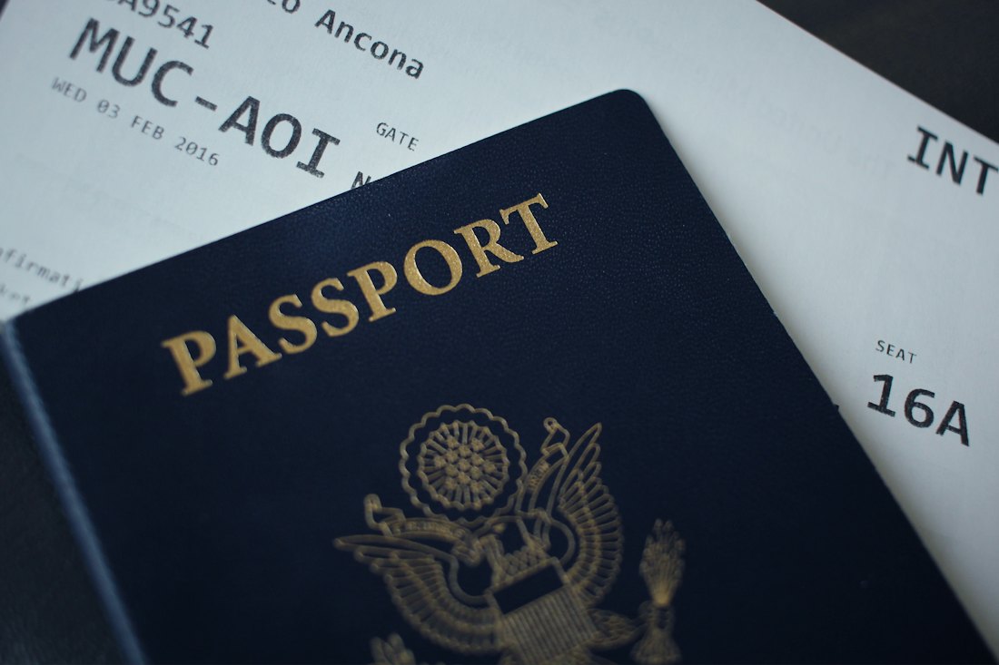 A dark blue passport resting on top of a printed boarding pass