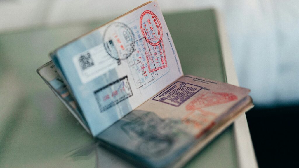 An open passport standing on a table, its pages covered in colourful entry and exit stamps