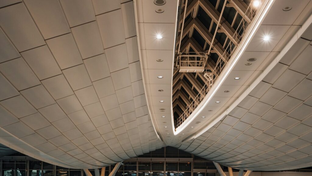 The curved, softly lit ceiling of a large airport departure hall at night